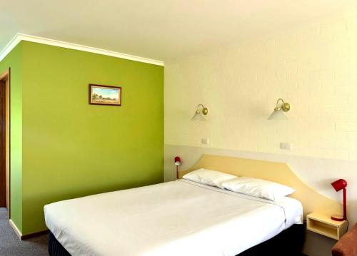 a bedroom with a green wall with a bed at Hepburn Springs Motor Inn in Hepburn Springs