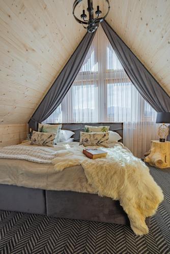 a bedroom with a large bed with a large window at Osada Poronin in Poronin