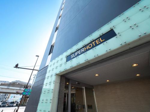 a building with a sign on the side of it at Natural Hot Spring Super Hotel Tottori Eki Kitaguchi in Tottori