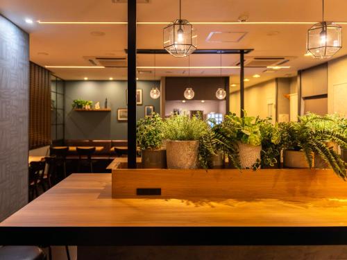 a dining room with potted plants on a table at Natural Hot Spring Super Hotel Tottori Eki Kitaguchi in Tottori