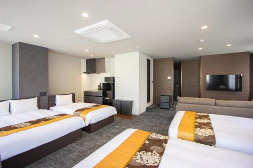 a hotel room with two beds and a flat screen tv at Hotel FUK O in Fukuoka