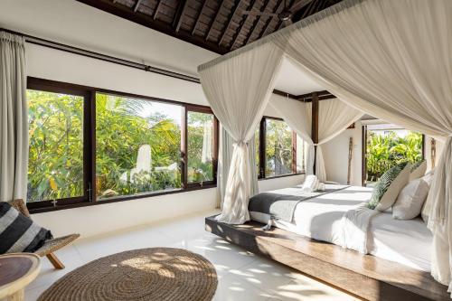 a bedroom with a bed and large windows at Fraser Baye Villas in Uluwatu