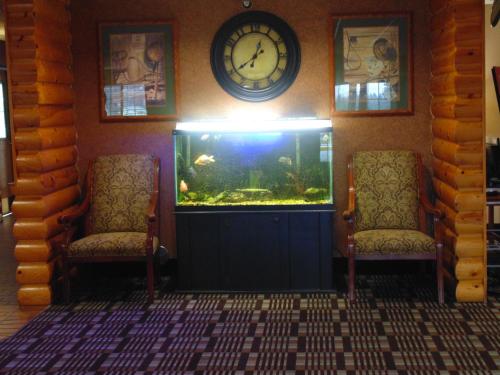 a room with a fish tank and two chairs and a clock at American Inn and Suites Houghton Lake in Houghton Lake