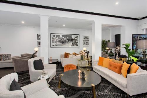 a living room with white furniture and orange pillows at CH Boutique Hotel & Apartments, an Ascend Collection Hotel in Tamworth