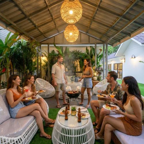 a group of people sitting on a patio eating food at Savana- Wild Pool Villa I 6 en-suite bedrooms in Chiang Mai