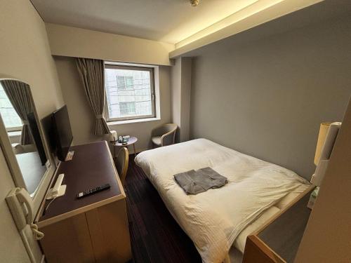 a small room with a bed and a window at Hotel Tetora Spirit Sapporo in Sapporo