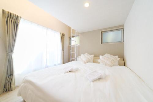 a white bed in a room with a window at JAPANDI HOTEL Nagoya in Chikusachō