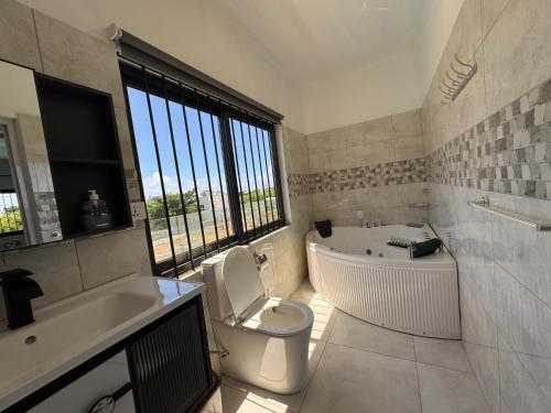 a bathroom with a tub and a toilet and a sink at Authentica Private Villa by Oceanaxe Holidays in Calodyne