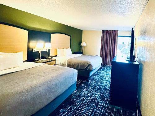 a hotel room with two beds and a television at Quality Inn Conference Center Logansport in Logansport