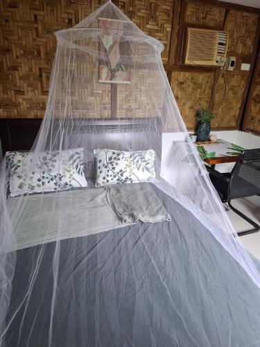 a bed with a net on top of it at Nipaville Haven in Moalboal