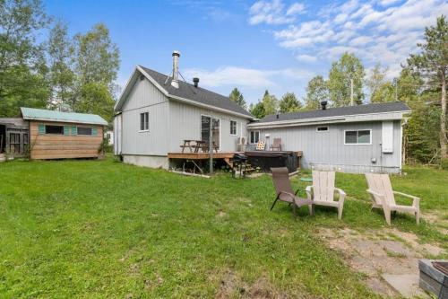 a yard with two chairs and a house at Spa - River & Forest View - Le Petit Cocon in Chateau Richer