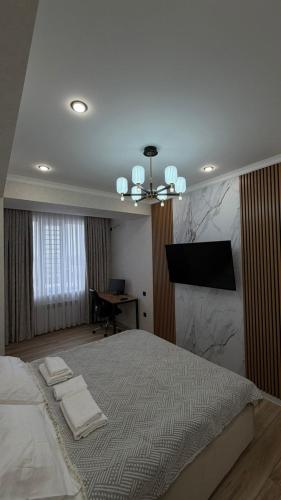 ein Schlafzimmer mit Bett, Schreibtisch und Fernseher in der Unterkunft Millennium in Bischkek