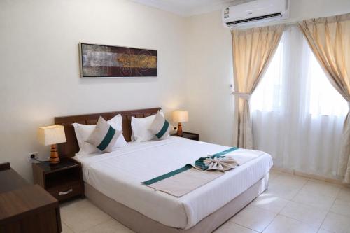 a bedroom with a large white bed and a window at Almawasem Alarbaa for Serviced Apartments - Standard in Al Jubail