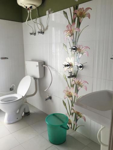 a bathroom with a toilet and a flower pattern on the wall at Hotel Aditya in Aritar