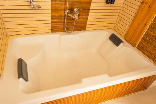 a white bath tub in a room with wooden walls at Conifer Suites & Spa Darjeeling in Darjeeling