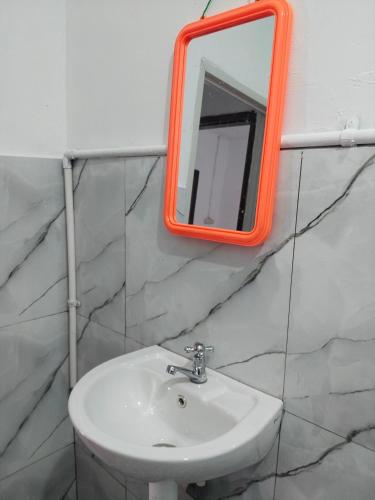 an orange mirror above a sink in a bathroom at EL Homestay Bunaken in Bunaken