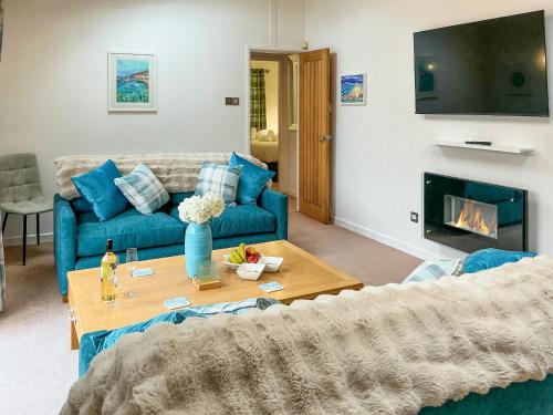 a living room with a blue couch and a fireplace at 9 Trehawks in Roche