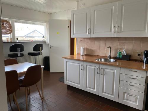 a kitchen with white cabinets and a table with a sink at Charming Private Apartment in a Villa by the Forest in Sønderborg
