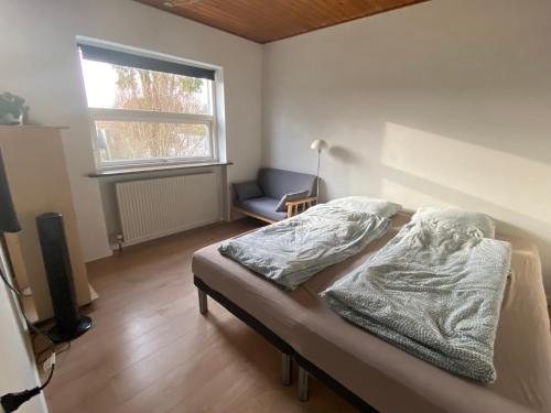 a bedroom with a bed and a chair and a window at Charming Private Apartment in a Villa by the Forest in Sønderborg