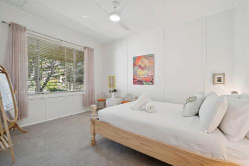 a white bedroom with a bed and a window at Misty Pines in Leura