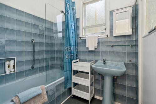 a blue tiled bathroom with a sink and a shower at Misty Pines in Leura