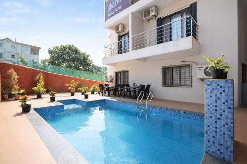 a swimming pool in front of a house at FabHotel Sharvi in Mahabaleshwar