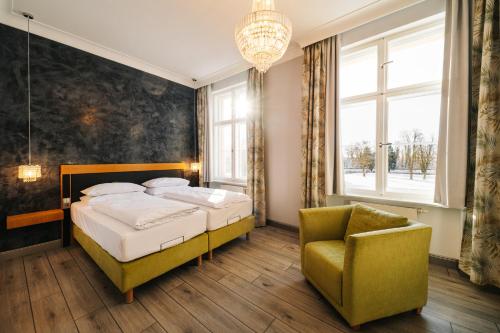 a bedroom with a bed and a chair and a chandelier at Schloss und Gut Liebenberg in Liebenberg