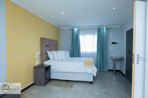 a bedroom with a white bed and a window at Towny Lodge in Kokstad