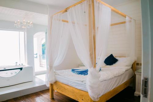 a bedroom with a canopy bed and a sink at Ezrah coastal boutique hotel el nido in El Nido
