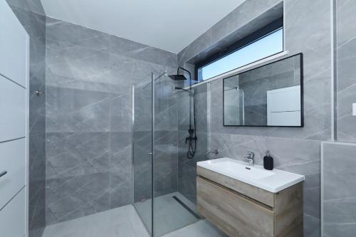 ein Badezimmer mit Dusche, Waschbecken und Spiegel in der Unterkunft Astur in Zadar