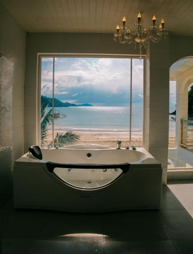 a bath tub in a room with a view of the beach at Ezrah coastal boutique hotel el nido in El Nido