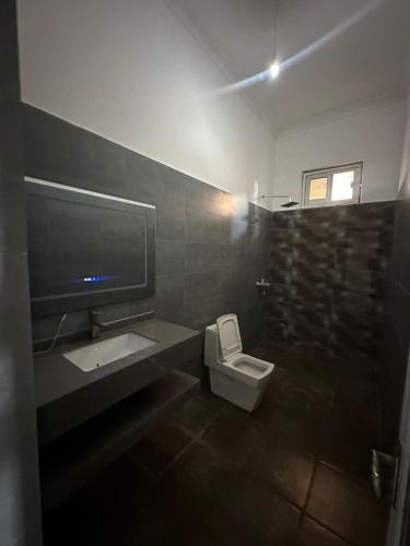 a bathroom with a toilet and a sink and a tv at Paje staycation apartment in Paje