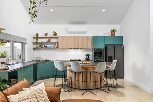 a kitchen with green cabinets and a table and chairs at The Ausly Architectural Coastal Retreat with pool pet friendly in Aldinga Beach