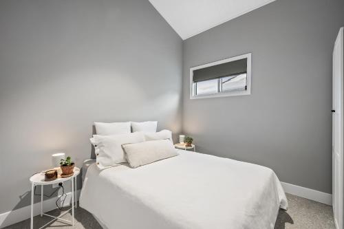 a white bedroom with a white bed and a window at The Ausly Architectural Coastal Retreat with pool pet friendly in Aldinga Beach