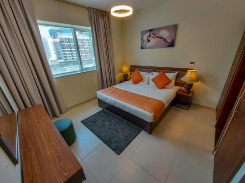 a bedroom with a bed and a table and a window at Grand Stay Holiday Homes Rental in Dubai