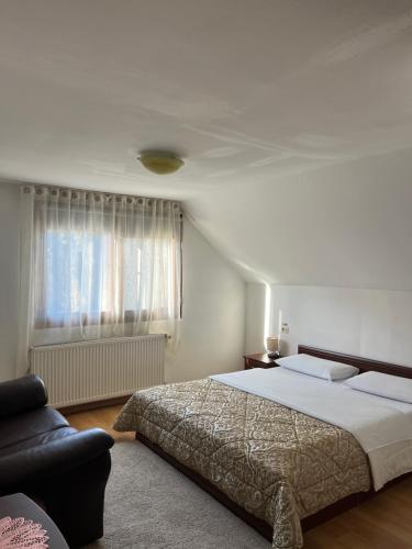 a bedroom with a bed and a couch and a window at Cazare Luxandra in Borşa