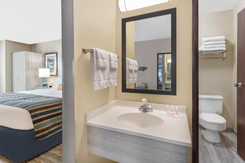een badkamer met een wastafel, een bed en een spiegel bij SilverStone Inn & Suites Spokane Valley in Spokane Valley