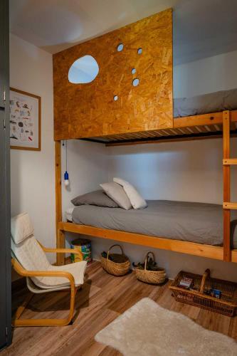 a bedroom with two bunk beds and a chair at La p'tite Lulu in Le Petit Chenevey
