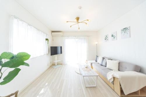 a white living room with a couch and a tv at Miraie Yokkaichi Hazunaka in Yokkaichi