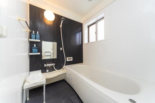 a bathroom with a white tub and a shower at Miraie Yokkaichi Hazunaka in Yokkaichi