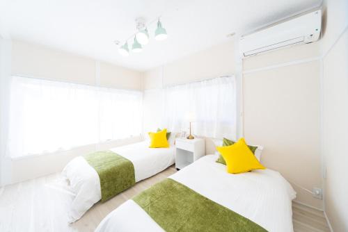 two beds in a white room with yellow pillows at Miraie Yokkaichi Hazunaka in Yokkaichi