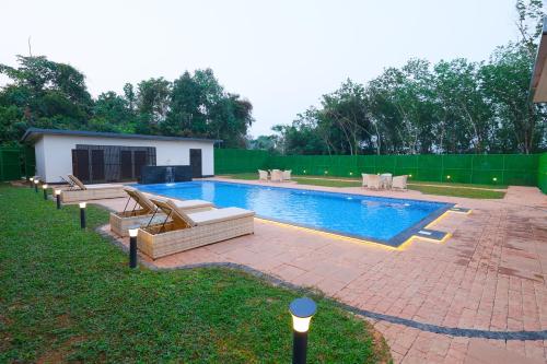 a swimming pool with lounge chairs in a yard at B Town Resort Near Infopark Kakkanad in Kakkanad