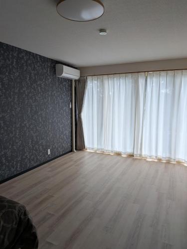 an empty living room with a large window and wooden floors at T&T Fujiyama MC2 in Iiyama