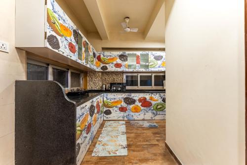 a kitchen with a counter with fruits and vegetables on the wall at Gauri Villa by ELIVAAS With Pool, Lounge, Garden & Bathtub With 360 Panoramic Hill Views Near Waterfalls in Kasāra