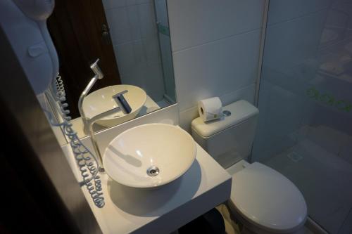 a bathroom with a white sink and a toilet at Pousada Aguas Claras in Búzios