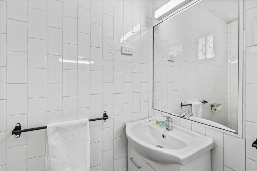 a white bathroom with a sink and a mirror at Annerley Motor Inn in Brisbane