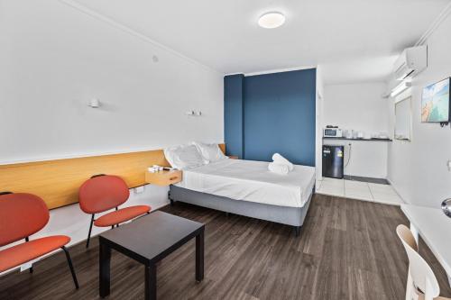 a small room with a bed and two chairs at Annerley Motor Inn in Brisbane