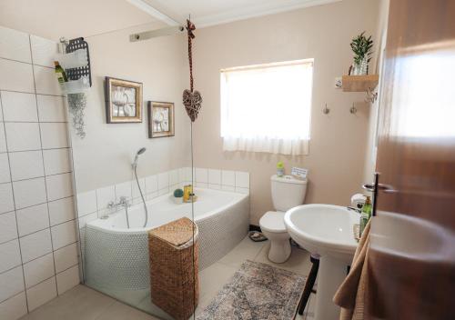a bathroom with a tub and a toilet and a sink at AllesWells in Yzerfontein