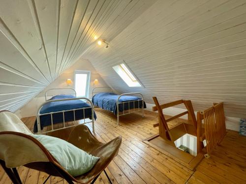 a attic room with two beds and a chair at Landhaus am Deich in Dornum