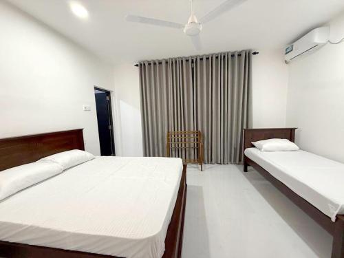 a bedroom with two beds and a chair in it at Royal Star Guest House in Jaffna